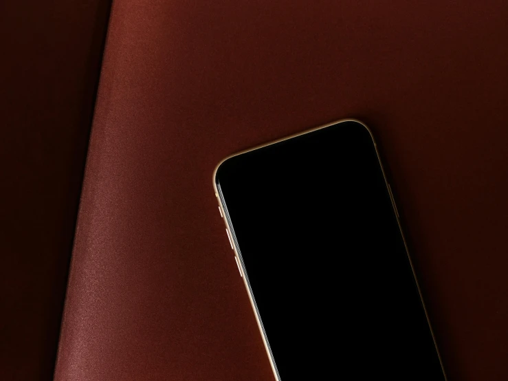 a cell phone sitting on top of a red chair, by Emma Andijewska, trending on pexels, minimalism, black fine lines on warm brown, gold inlay, medium closeup, leather padding