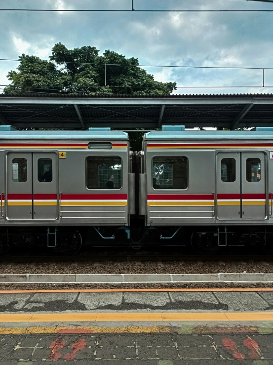 a silver train pulling into a train station, by Hiroshi Honda, unsplash, train with maroon, adult pair of twins, panoramic, mrt