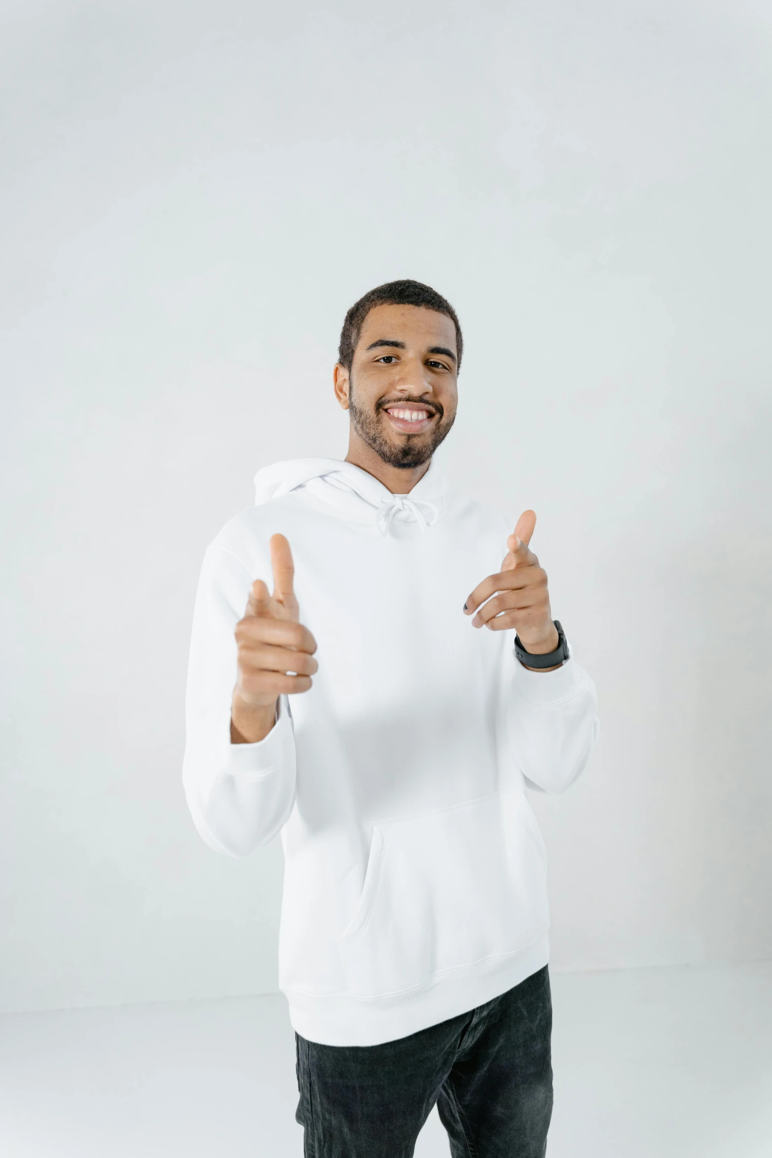 a man in a white hoodie giving a thumbs up, white backdrop, luis melo, day time, black man
