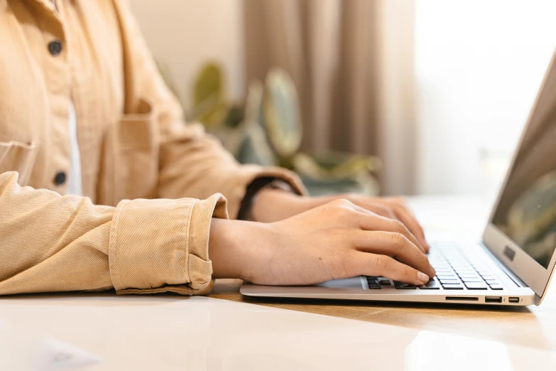 a close up of a person typing on a laptop, trending on pexels, brown, lightly dressed, realistic parallel content, feminine looking