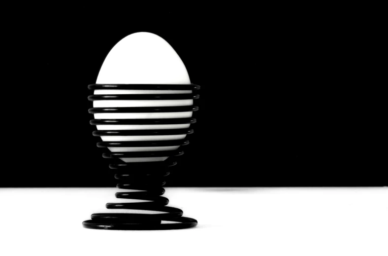 a white egg sitting on top of a black stand, a raytraced image, inspired by Robert Mapplethorpe, op art, modern high sharpness photo