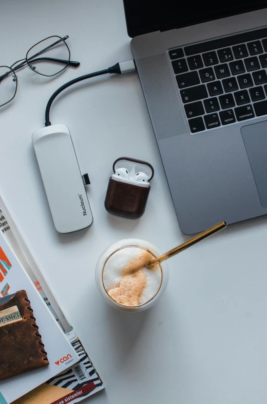 a laptop computer sitting on top of a desk next to a cup of coffee, trending on pexels, happening, holding a small vape, brown and white color scheme, white and orange, eating mars bar candy