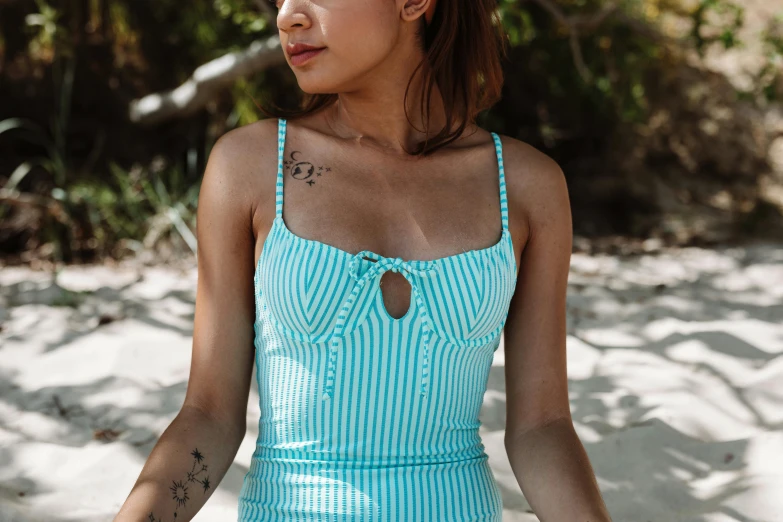 a woman sitting on top of a sandy beach, a portrait, inspired by Mardi Barrie, unsplash, in retro swimsuit, close up front view, malaysian, light blue