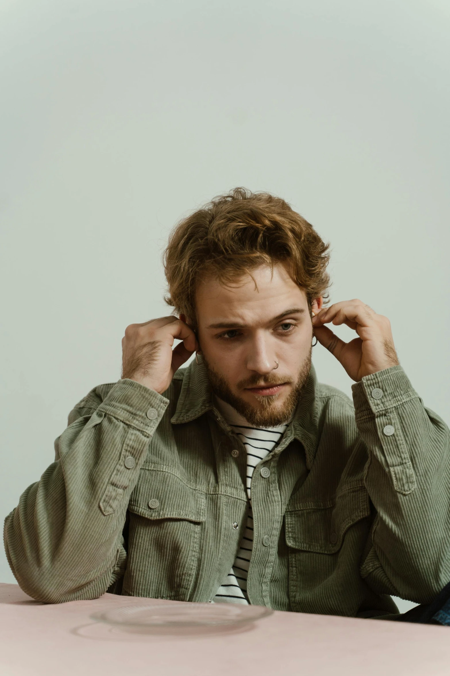 a man sitting at a table with a plate of food in front of him, a colorized photo, inspired by James Morrison, pewdiepie, looking to the side off camera, on a gray background, curls on top of his head