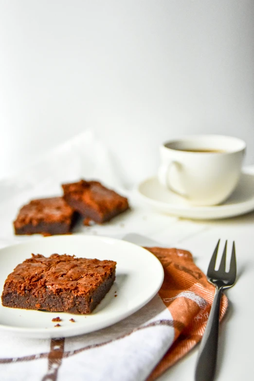 a white plate topped with brownies next to a cup of coffee, by Jessie Algie, unsplash, square, orange, auburn hair, 15081959 21121991 01012000 4k