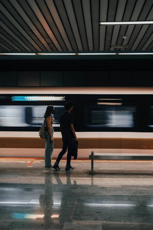 the man and woman are standing together in front of the train