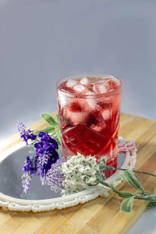 a drink with berries and a flower is next to a mirror