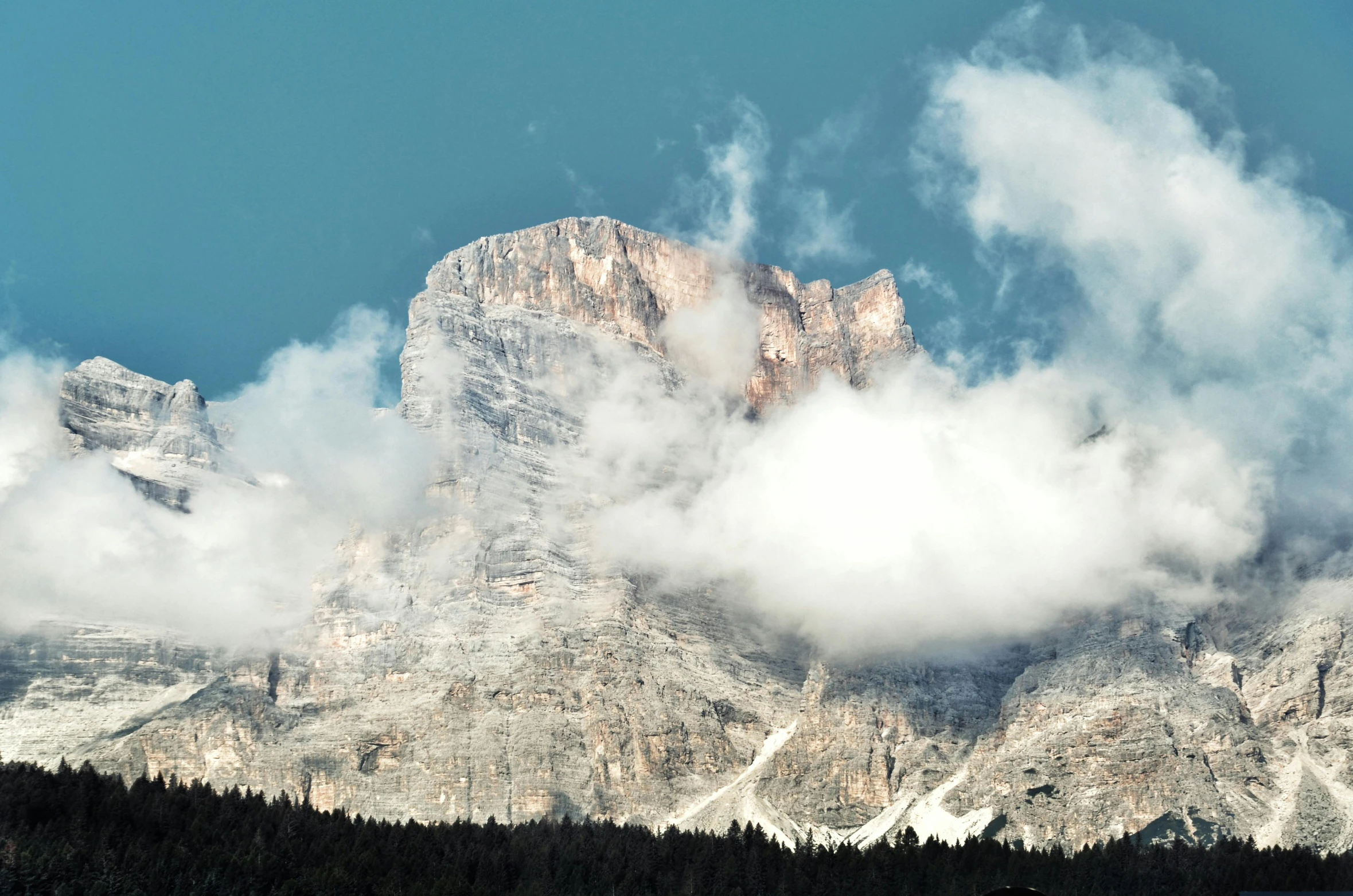 a large mountain with snow capped peaks covered in clouds