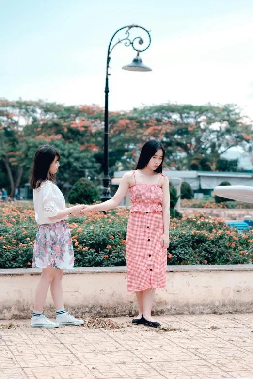 a couple of women standing next to each other, a picture, by Tan Ting-pho, unsplash, realism, holding hand, summer day, ( ( theatrical ) ), bad quality