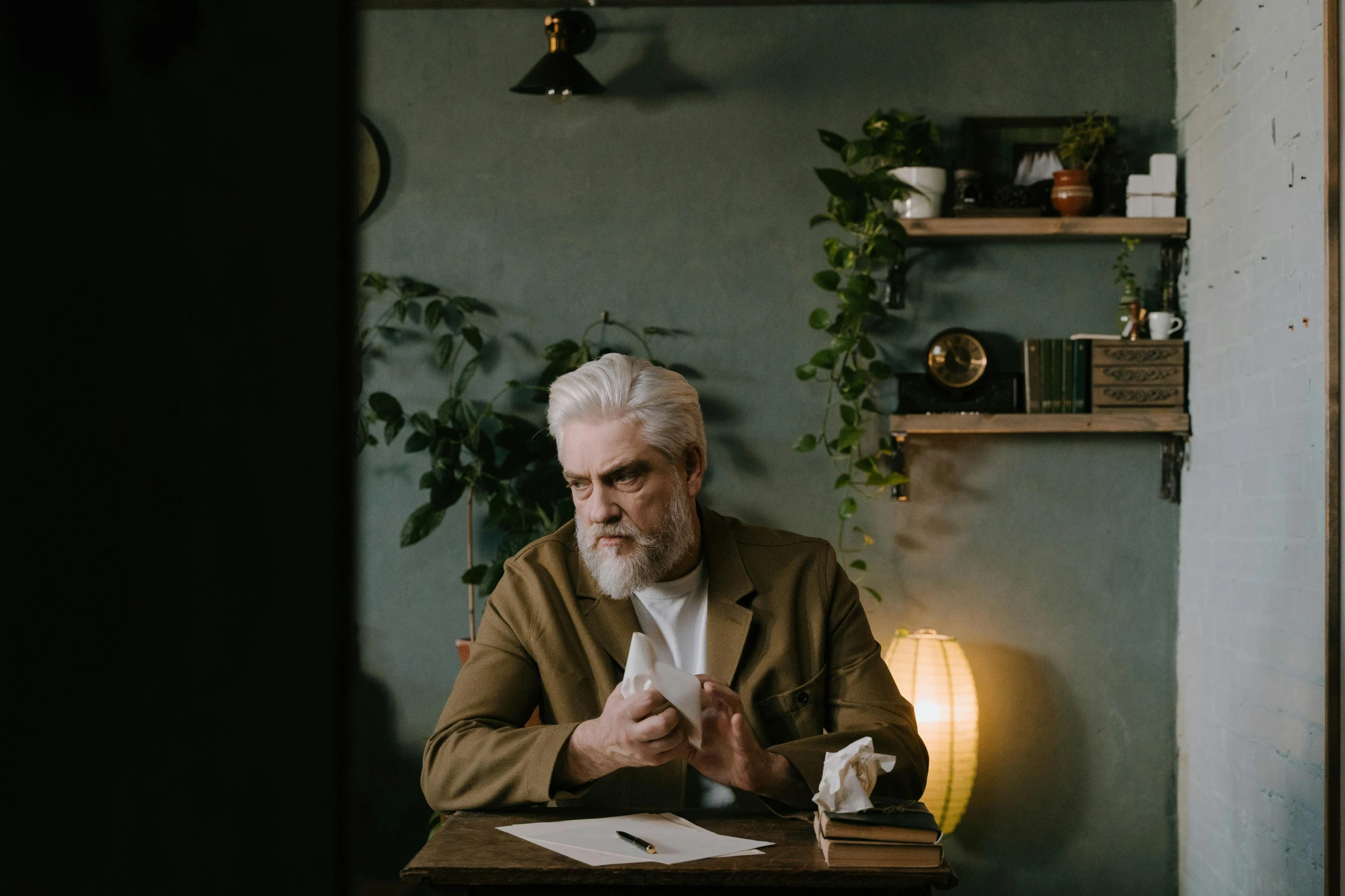 an old man with gray hair sitting in front of a desk