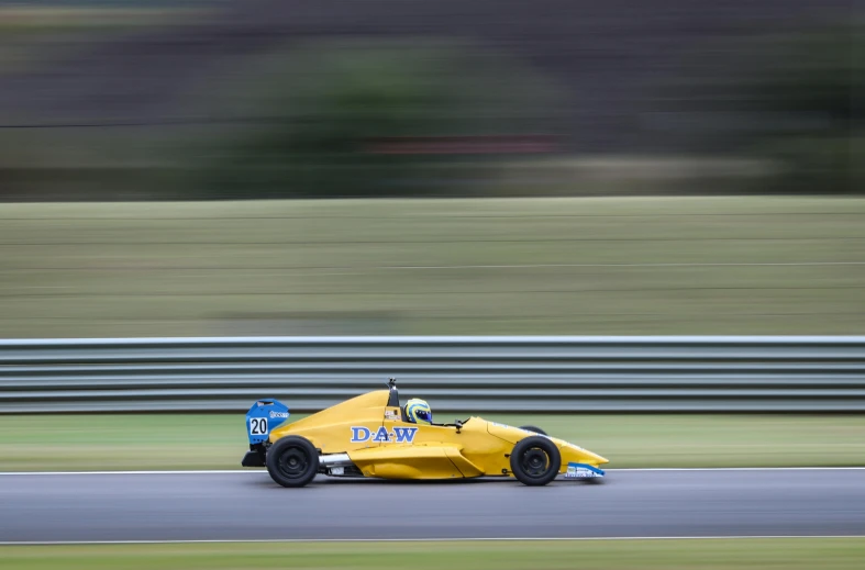 a man driving a yellow race car on a track