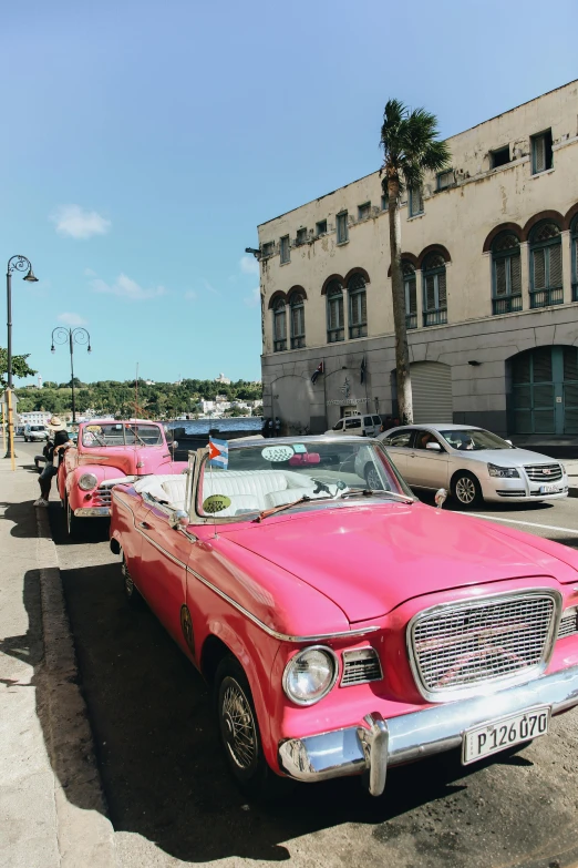 pink cars parked along the curb in a city