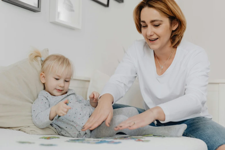 a woman playing with a child on a bed, pexels contest winner, with fingers, casually dressed, animation, low quality photo