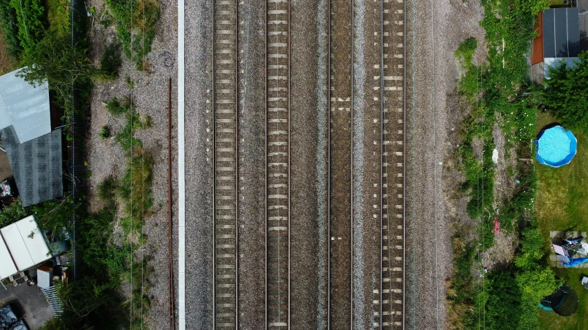 a train traveling down train tracks next to a lush green forest, inspired by Andreas Gursky, birds eye overhead perspective, demur, square lines, kai vermehr