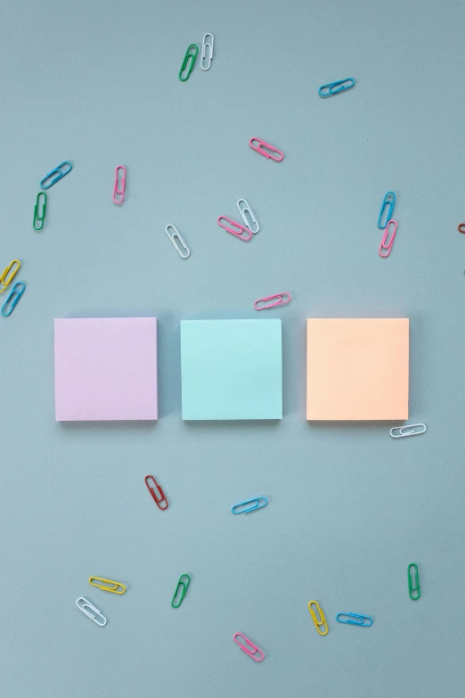 a group of paper clips sitting on top of a blue surface, an album cover, trending on unsplash, color field, candy pastel, square sticker, rgb wall light, 15081959 21121991 01012000 4k