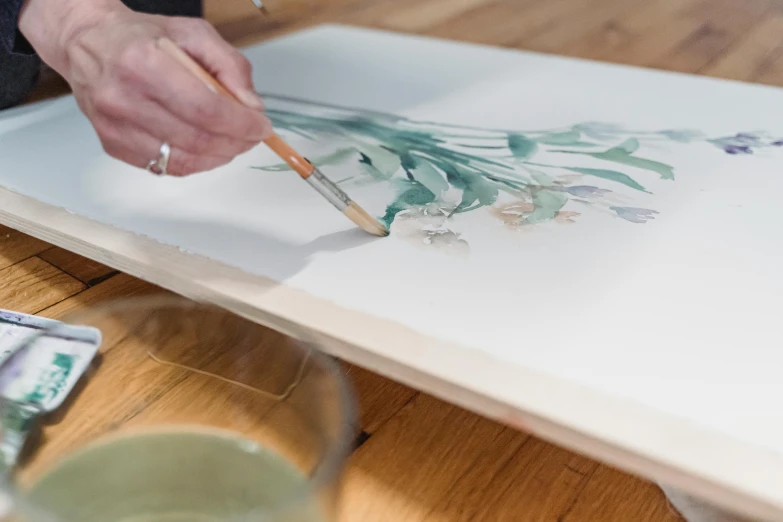 a person is painting flowers on a piece of paper, a watercolor painting, inspired by Constantin Hansen, on a wooden tray, pouring techniques, eucalyptus, commission art