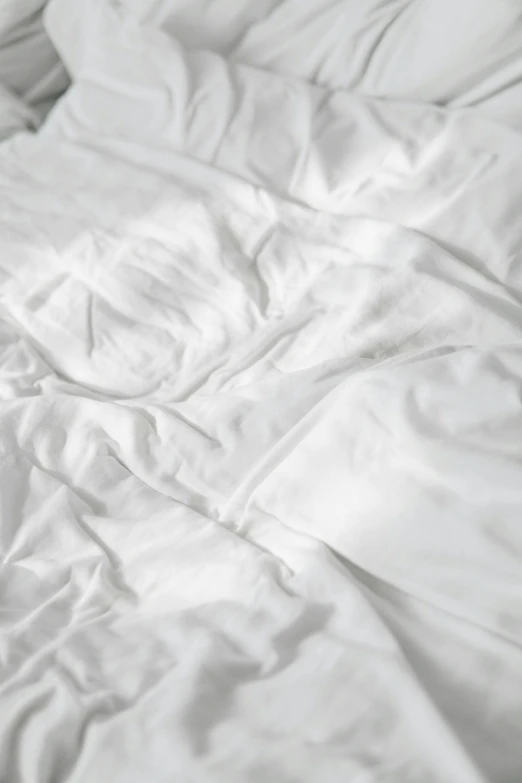 an unmade bed with white sheets and pillows, seams stitched tightly, swirling fabric, promo image, white-space-surrounding