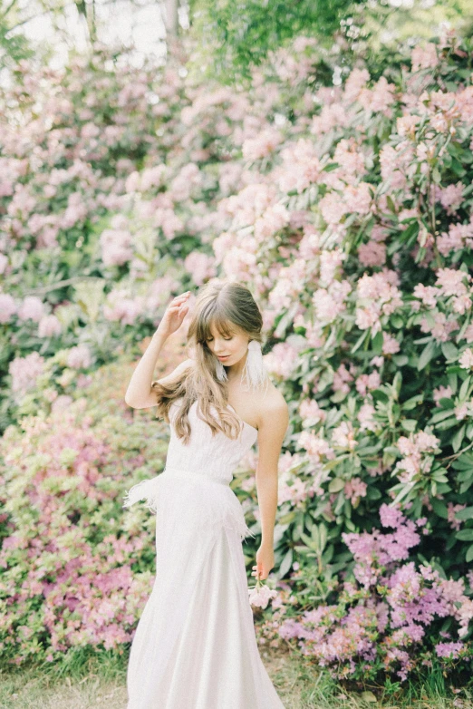 a woman in a wedding dress standing in front of flowers, inspired by Oleg Oprisco, unsplash, lilac, low quality photo, made of flowers, white and pink