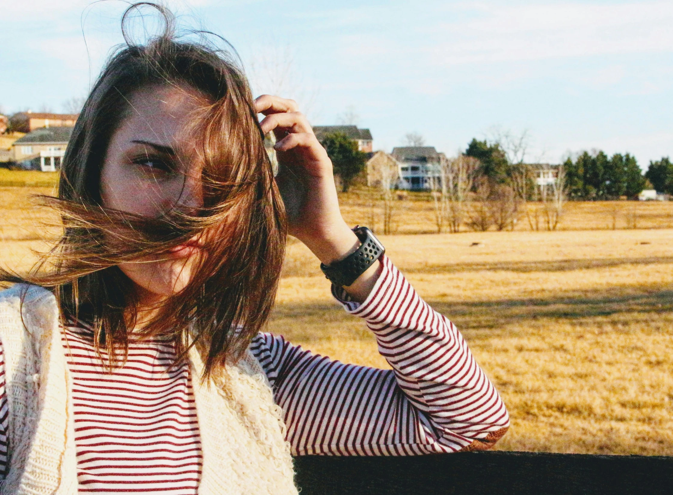 a woman with her hair blowing in the wind, by Carey Morris, trending on unsplash, wearing stripe shirt, young southern woman, very bushy brown hair, photo taken with provia