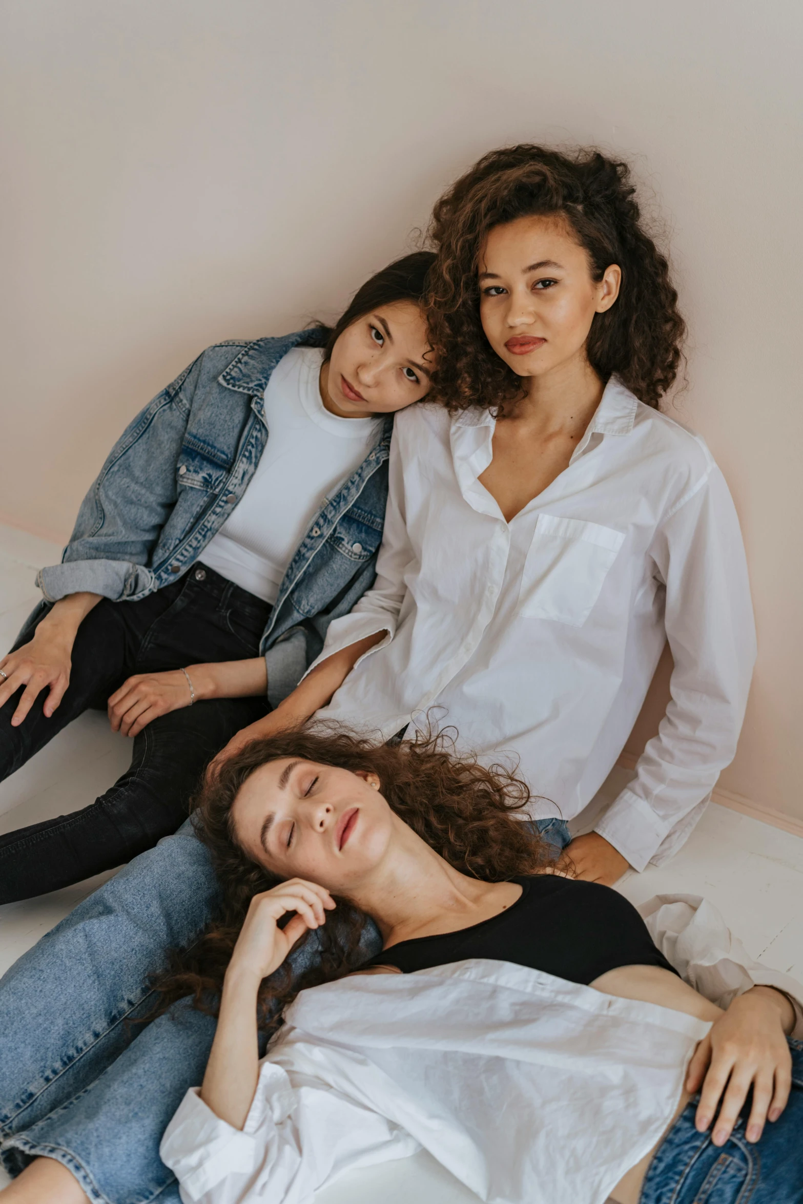 three women sitting next to each other on a bed, inspired by Raphael Soyer, trending on pexels, arm around her neck, curls, portrait sophie mudd, mixed race