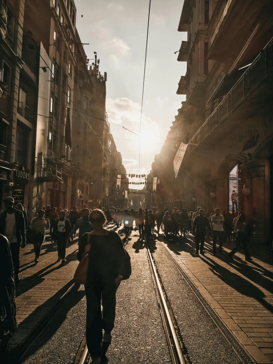 a group of people walking down a street next to tall buildings, a picture, pexels contest winner, happening, some sunlight ray, istanbul, gothic quarter, street tram