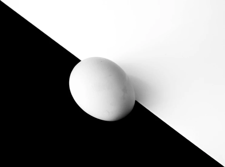 a white egg sitting on top of a black and white wall, an ambient occlusion render, inspired by Robert Mapplethorpe, unsplash, minimalism, abstract claymation, diagonal, 15081959 21121991 01012000 4k, high shadow