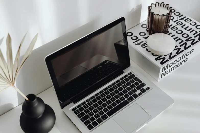a laptop computer sitting on top of a white desk, unsplash, black and silver, glowing details, background image