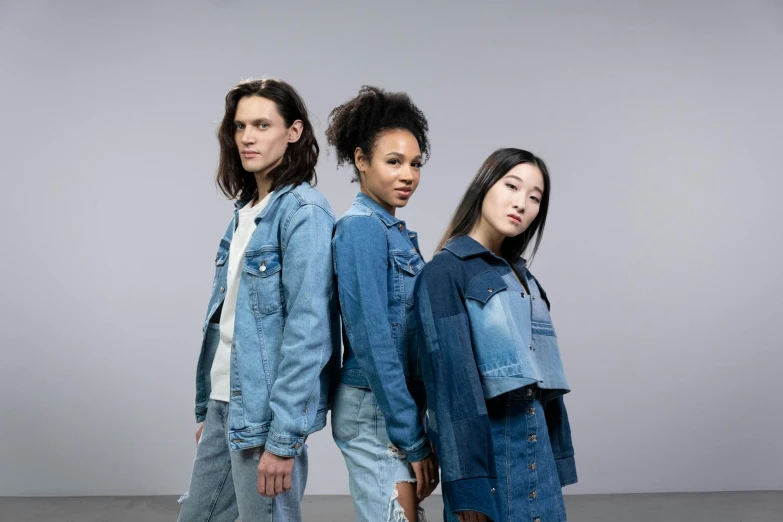 two girls and one boy standing together wearing jean jackets