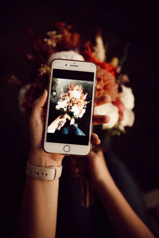 a close up of a person holding a cell phone, a picture, by Julia Pishtar, romanticism, bouquets, photograph”