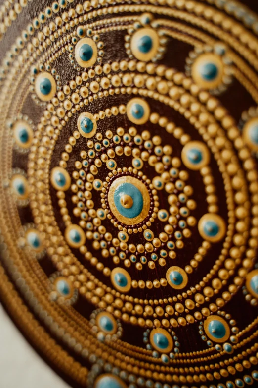 a close up of a decorative object on a table, mandala art, turquoise gold details, dot art, chocolate art