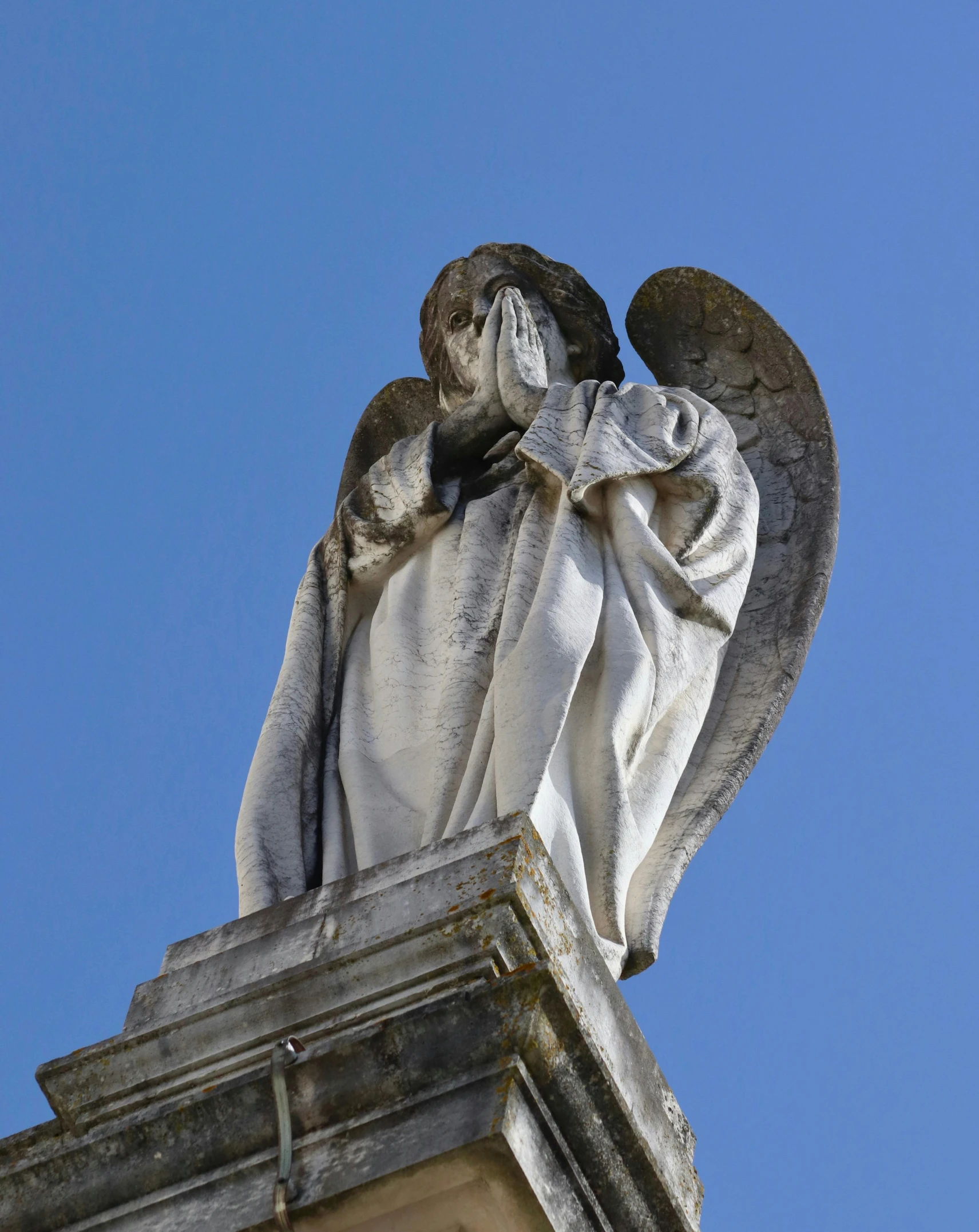 a statue of an angel on top of a building, head bowed slightly, silver wings, tombstone, blue sky