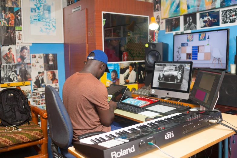 a man sitting at a desk in front of a keyboard, an album cover, by Ella Guru, pexels, emmanuel shiru, in a studio, in the center of the image, mixing