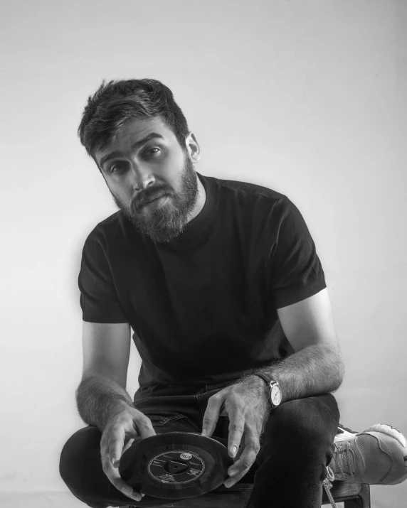 a black and white photo of a man sitting on a skateboard, by Adam Dario Keel, hurufiyya, a portrait of rahul kohli, with a beard and a black shirt, dj sura, discord profile picture