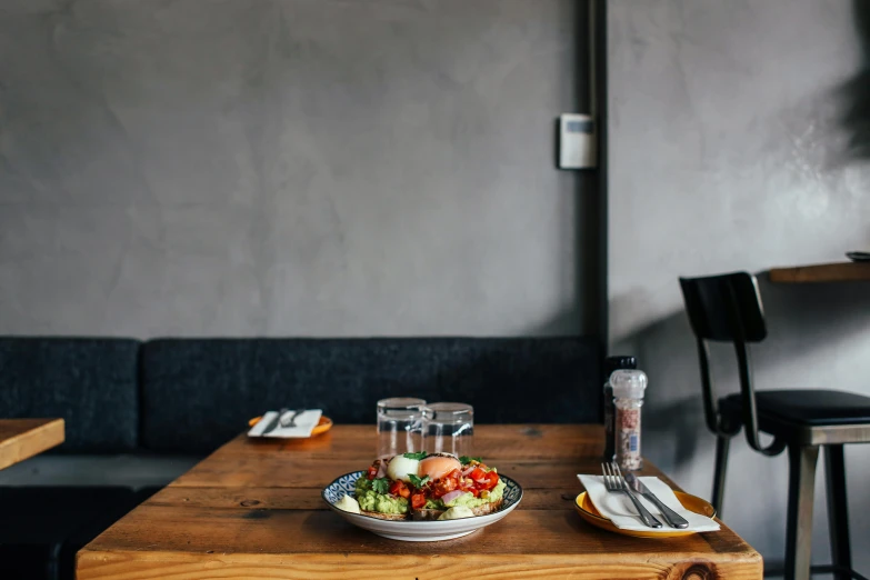 a wooden table topped with a bowl of food, by Daniel Lieske, pexels contest winner, overcast day, american canteen, sitting down casually, mixed materials