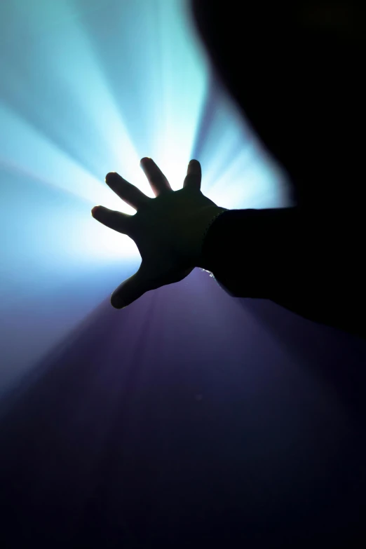 a person holding their hand up in the dark, an album cover, light and space, light beam, silhouetted, volumetric light from above, reaching out to each other