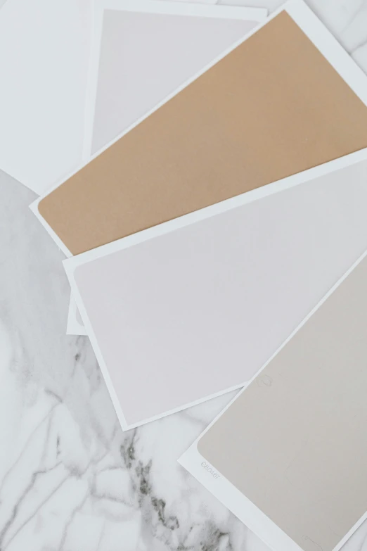 a bunch of paint samples sitting on top of a marble counter, a picture, beige, sleek white, background image, cards