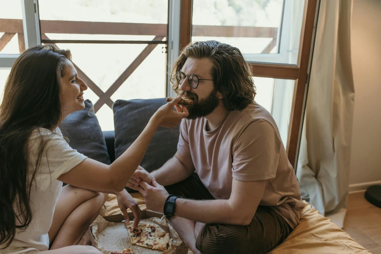 a man and a woman sitting on a bed eating pizza, by Lee Loughridge, pexels contest winner, lachlan bailey, cake, profile image, cottagecore hippie