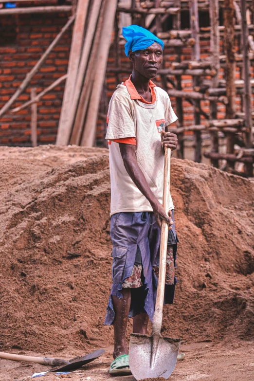 a man with a shovel standing in front of a pile of dirt, inspired by Afewerk Tekle, pexels contest winner, happening, teenage boy, tall thin build, adut akech, carpenter