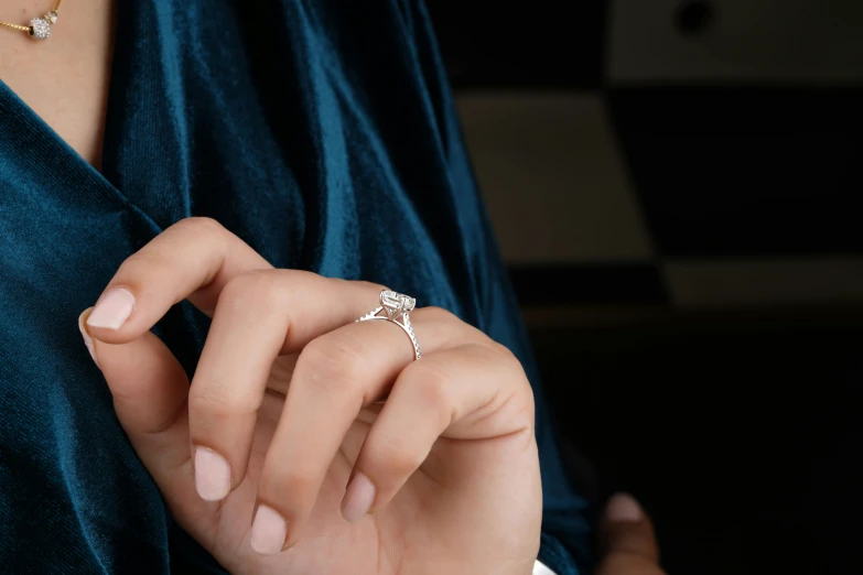 a close up of a person wearing a ring, back towards camera, advert, large diamonds, hand on table