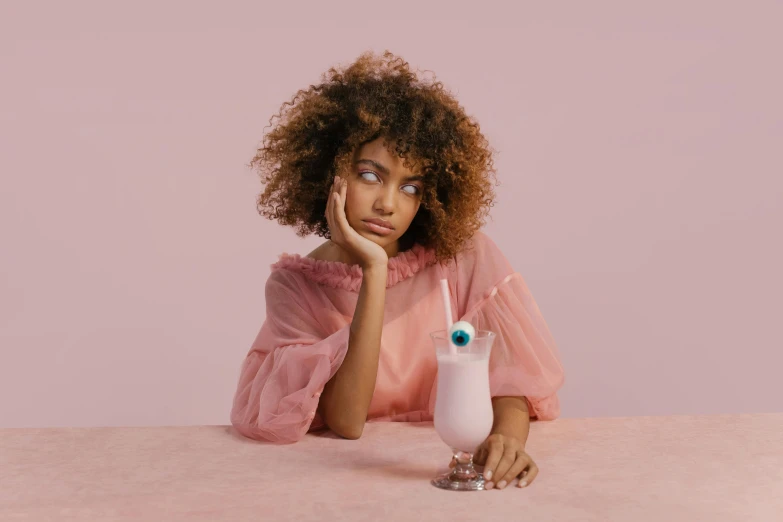 a woman sits with her hand on the side of a glass looking off to the side