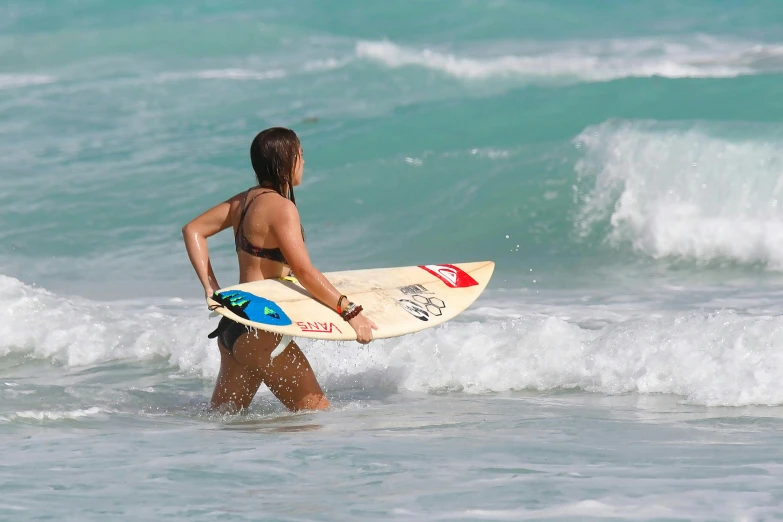 a woman walking out of the ocean with a surfboard, by Nina Hamnett, pexels contest winner, emily ratajkowski, nina dobrev, varadero beach, waves and splashes