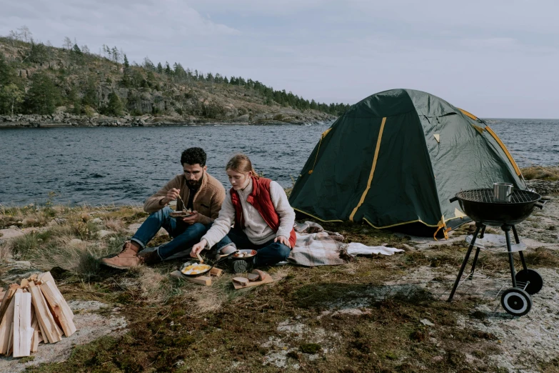 a couple of people sitting in front of a tent, by Jaakko Mattila, pexels contest winner, food. craft and adventure, on the ocean, two male, youtube thumbnail