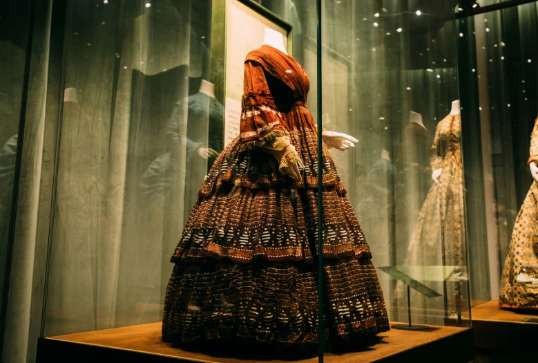 a woman's dress on display in a glass case, inspired by Anna Füssli, pexels contest winner, red and gold cloth, wearing 1 8 5 0 s clothes, in australia, collection of louvre