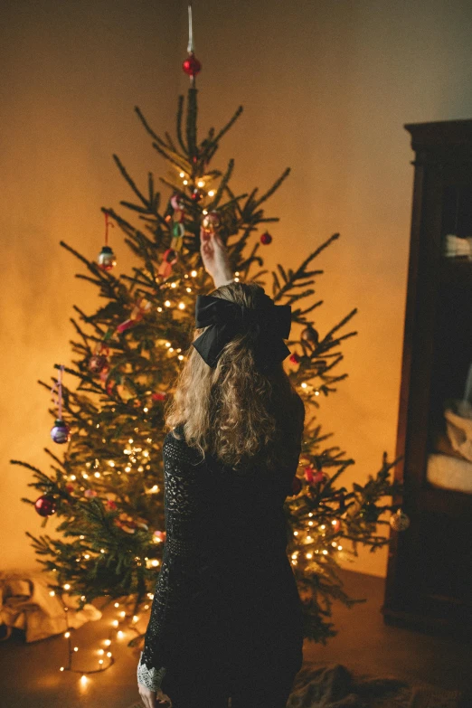 a woman standing next to a christmas tree