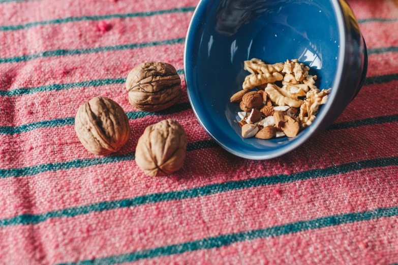 a blue bowl filled with nuts on top of a table, by Julia Pishtar, trending on unsplash, antipodeans, on a velvet tablecloth, having a snack, detail shot, listing image