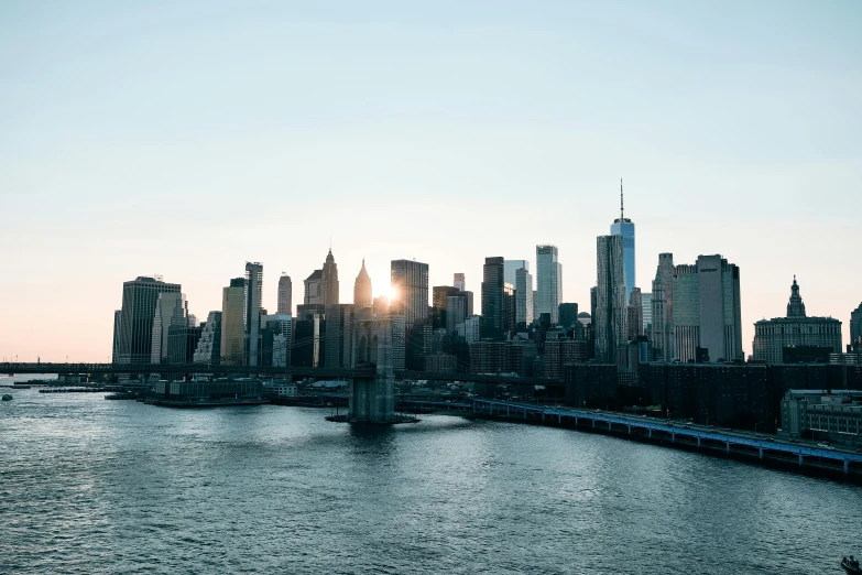 a large body of water with a city in the background, pexels contest winner, golden hour in manhattan, instagram post, industrial gotham city, sun and shadow over a city