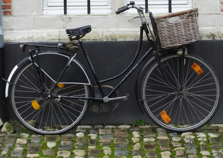 a bicycle parked against a wall with a basket on it, black sokkel, profile image, normandy, black