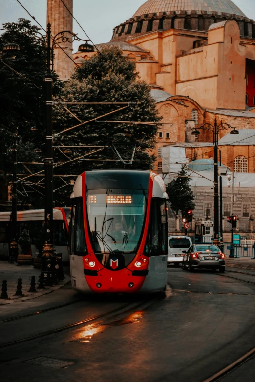 a red and white train traveling down a street next to a tall building, pexels contest winner, street tram, thumbnail, turkish and russian, gif