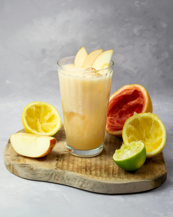 a glass filled with fruit sitting on top of a cutting board, product image, vanilla, apple orange, milkshake