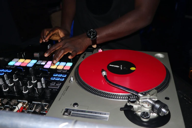 a close up of a dj playing music on a turntable, pexels, private press, red and gold cloth, adut akech, red and grey only, in house